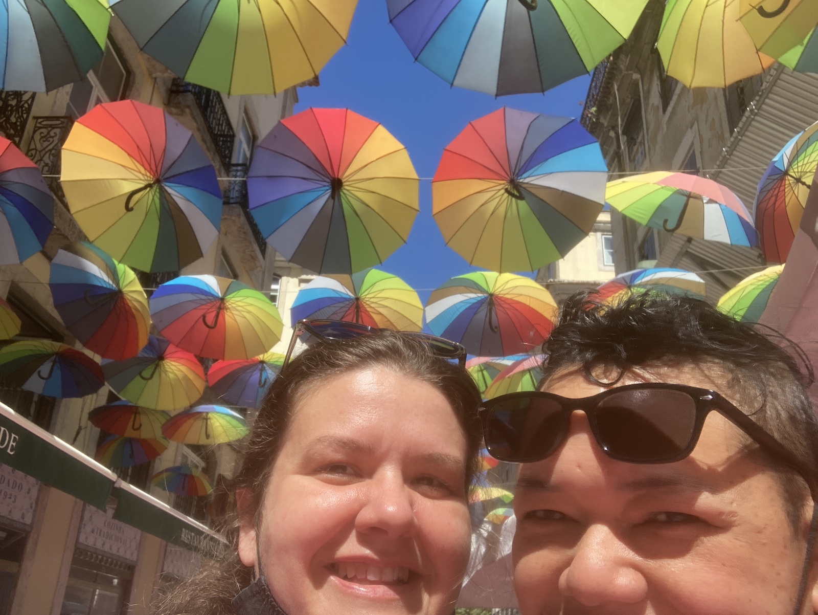 Charity and Maylene stand under rainbow umbrellas