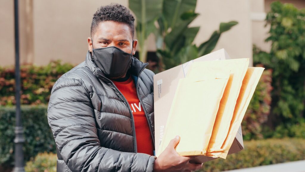 Delivery person with a bundle of manila envelopes ready for mail delivery. These can be scanned by a virtual mailbox service.